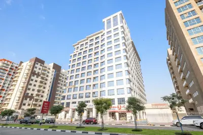 a tall white building with cars parked in a city at Silkhaus Luxury Studio in Residential Neighborhood in Dubai