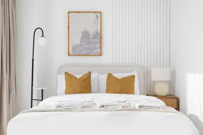 a white bedroom with a white bed with gold pillows at Silkhaus Luxury Studio in Residential Neighborhood in Dubai