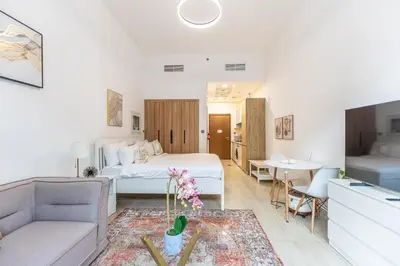 a bedroom with a bed and a living room at HAVN - Studio Apartment in Pantheon Elysee, JVC in Dubai