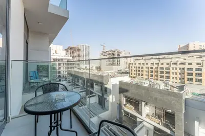 a balcony with a table and a view of a city at HAVN - Smart Home Studio in Oxford 212, JVC in Dubai