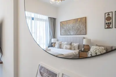 a mirror reflecting a room with a bed and a couch at HAVN - Smart Home Studio in Oxford 212, JVC in Dubai