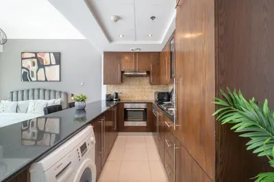 a kitchen with wooden cabinets and a dishwasher at HAVN - Studio Unit in 8 Boulevard, Downtown Dubai in Dubai