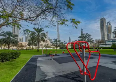 a red bike rack in a park with tall buildings at HAVN - Studio Unit in 8 Boulevard, Downtown Dubai in Dubai
