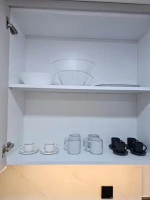 a shelf with cups and saucers in a kitchen at Cozy Studio - Dubai Marina - 5 Min to Beach and Metro in Dubai