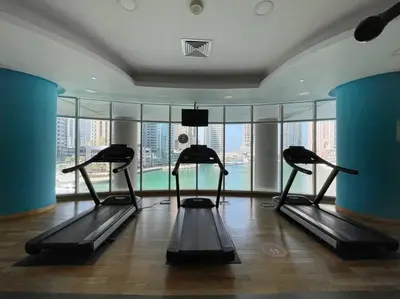 a gym with several treadmills in a room with windows at The Smart Concierge - Avant in Dubai