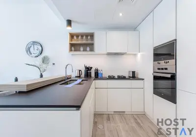 a kitchen with white cabinets and a counter top at Unique 1BR in Belgravia Square, JVC - Host & Stay in Dubai