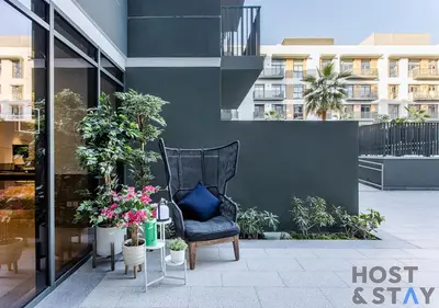 a black chair with a blue pillow sitting on a patio at Unique 1BR in Belgravia Square, JVC - Host & Stay in Dubai