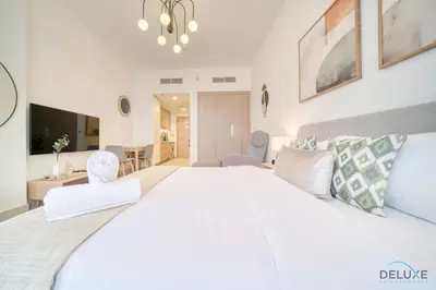 a bedroom with a large white bed and a living room at Beautiful Studio at Azizi Riviera 17, Al Merkadh by Deluxe Holiday Homes in Dubai