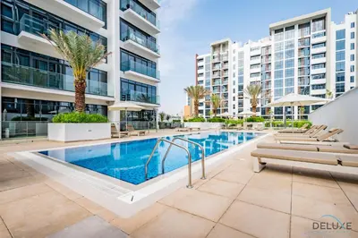 a swimming pool with chaise lounges next to a building at Beautiful Studio at Azizi Riviera 17, Al Merkadh by Deluxe Holiday Homes in Dubai