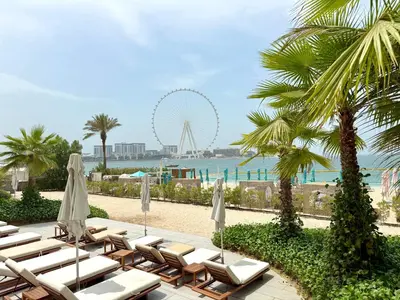 a beach with chairs and a ferris wheel in the background at 3Bed Private Beach - Belle vie à La Vie Dubai in Dubai