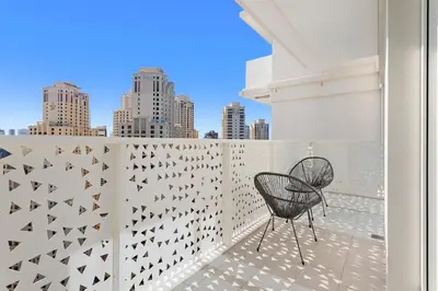 a chair on a balcony with a view of the city at Elegant and Modern 1BR Apt in JBR with Beach Access in Dubai