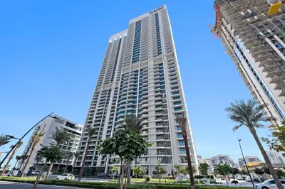 a tall building with palm trees in front of it at Amazing 2br with a lagoon view in Creek Harbour in Dubai