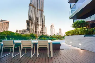 a table and chairs on a balcony with a city skyline at THE CLOSEST building to Burj Khalifa with Fountain View in Address Opera Residence in Dubai