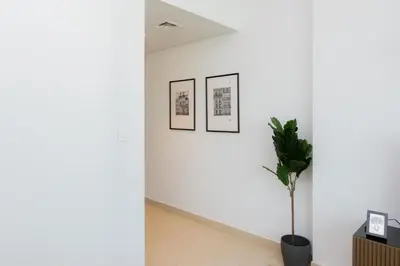 a hallway with three pictures on the wall and a potted plant at Elite Escape Holiday Home - 1 BHK Getaway with Dubai Mall Access - 1502 in Dubai
