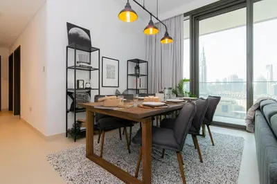 a dining room with a wooden table and chairs at Elite Escape Holiday Home - 3 BHK Getaway with Burj Khalifa View and Dubai Mall Access - 1505 in Dubai