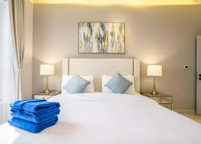 a bedroom with a white bed with blue sheets and two lamps at New Arabian Shams 2 JBR Sea View in Dubai
