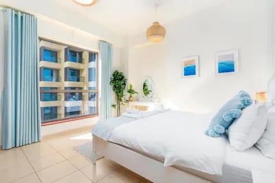 a white bedroom with a large bed and a window at 7 Beds / JBR / Sea, JBR Beach and Ain Dubai Views / 3 min walk from JBR Beach / Large Groups and Families / Ideal Vacation Location in Dubai