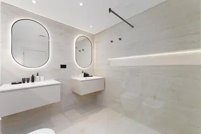 a white bathroom with two sinks and two mirrors at Luxury Living w private beach and Burj AlArab view in Dubai