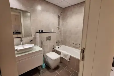 a bathroom with a toilet and a sink and a tub at Damac Hills Carson C studio with full kitchenet - Ideal for monthly stay in Dubai