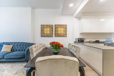 a living room with a table and a blue couch at HAVN - 2 Bedroom Apartment in Bloom Tower, JVC in Dubai
