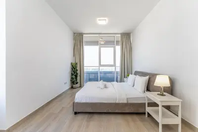 a white bedroom with a large bed and a window at HAVN - 2 Bedroom Apartment in Bloom Tower, JVC in Dubai