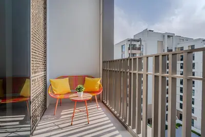 a balcony with a red chair and yellow pillows at Coastal Vibe I 1BDR apartment in Creek Beach I Summer 2 in Dubai