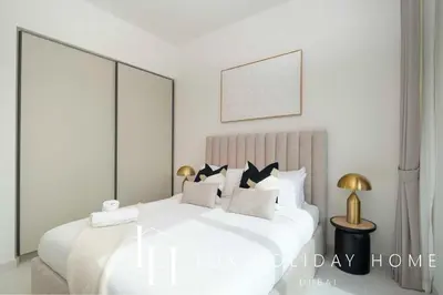 a white bedroom with a large white bed with pillows at LUX The Marina Vista Beachfront Suite in Dubai