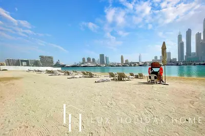a beach with chairs and a city in the background at LUX The Marina Vista Beachfront Suite in Dubai