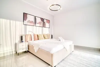 a white bedroom with a bed and a chandelier at Downtown Luxury - Stunning Burj Khalifa & Sea View - 5 Minutes Walk to Dubai Mall in Dubai