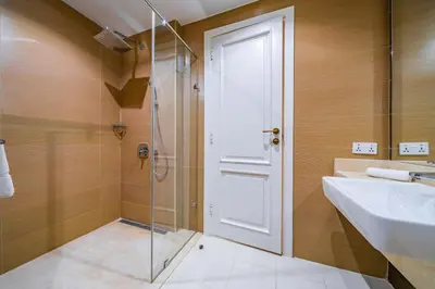 a bathroom with a glass shower door and a sink at SettlerHomes - Sparkle Tower 2 With Marina & Sea View in Dubai