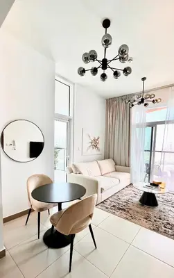a white living room with a table and a couch at Stylish & Roomy 1BR in the Heart of the City in Dubai