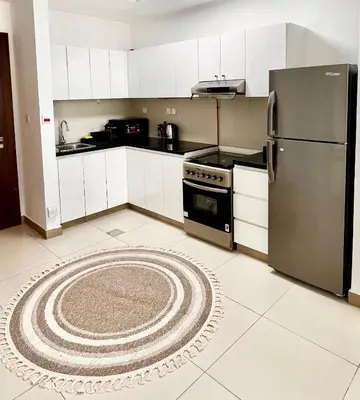 a kitchen with a refrigerator and a rug on the floor at Stylish & Roomy 1BR in the Heart of the City in Dubai