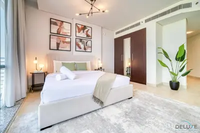 a bedroom with a white bed and a white couch at Grand Studio at Sky Gardens DIFC by Deluxe Holiday Homes in Dubai