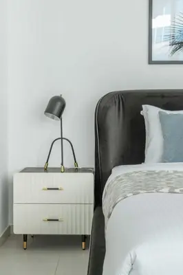 a black lamp on a night stand next to a bed at Frank Porter - Marquise Square Tower in Dubai