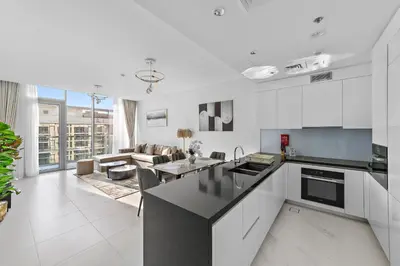 a kitchen with white cabinets and a living room at ALiving Classy 2BR I Lagoons View I District One Residence 7 in Dubai
