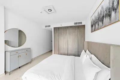 a white bedroom with a large bed and a mirror at ALiving Classy 2BR I Lagoons View I District One Residence 7 in Dubai