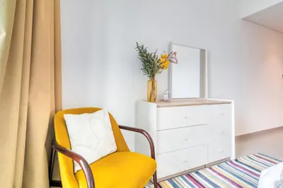 a yellow chair with a mirror and a dresser at Downtown - 2BR Apartment with Burj Khalifa View in Dubai
