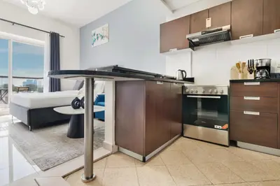 a kitchen with a table and a living room at Modern Sports City Studio Pool, Gym & Stadium in Dubai