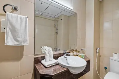 a bathroom with a sink and a toilet and a mirror at Modern Sports City Studio Pool, Gym & Stadium in Dubai