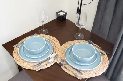 a table with blue plates and wine glasses on it at Modern Sports City Studio Pool, Gym & Stadium in Dubai