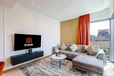 a living room with a couch and a tv at 1BR Gem with Stunning Marina Views, Close to Metro in Dubai