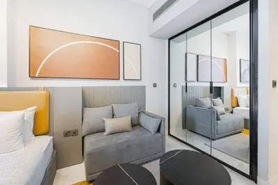 a bedroom with a bed and a chair and a mirror at Ravishing Studio at MAG 318, Business Bay in Dubai