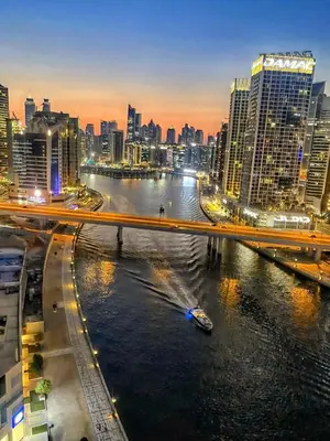 a boat on a river in a city at night at SkylineOasis1BR apt with BurjKhalifa & CanalView in Dubai