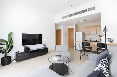 a living room with a couch and a tv and a kitchen at SkylineOasis1BR apt with BurjKhalifa & CanalView in Dubai
