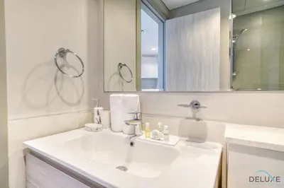 a white bathroom with a sink and a mirror at Canal Views! Promotional Rate on Lovely 1BR by Deluxe Holiday Homes in Dubai
