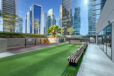 a green lawn in a building with benches and buildings at Canal Views! Promotional Rate on Lovely 1BR by Deluxe Holiday Homes in Dubai