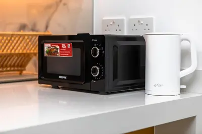 a black microwave sitting on a counter next to a cup at Luxury apartments at La Vie in Dubai