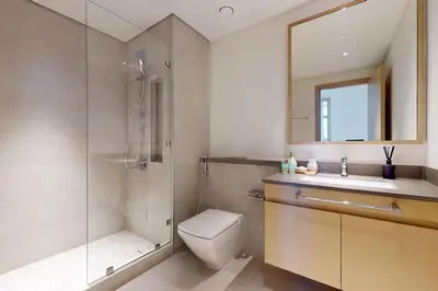 a bathroom with a shower and a toilet and a sink at Locations I Creek Harbor I Premium Modern 2BR I Luxury Interiors & Comfortable Stay I Close to Dubai Canal, Dining & Shopping I Pool, Gym & Parking in Dubai