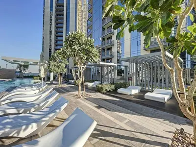 a row of chaise lounges in a courtyard with buildings at Locations I Creek Harbor I Premium Modern 2BR I Luxury Interiors & Comfortable Stay I Close to Dubai Canal, Dining & Shopping I Pool, Gym & Parking in Dubai