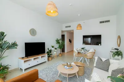 a living room with a couch and a tv at Elite Escape Holiday Home - 2 BHK Getaway with Burj Khalifa View and Dubai Mall Access - 1504 in Dubai